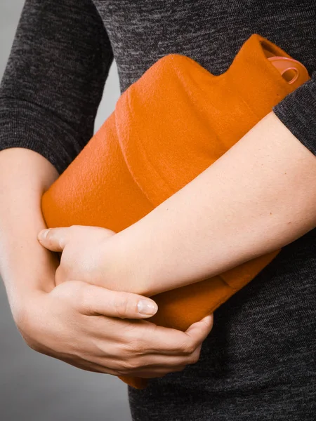 Girl having stomach ache, holding hot water bottle — Stock Photo, Image