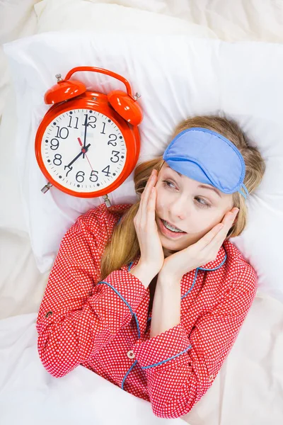 Shocked woman wearing pajamas holding clock overslept — Stock Photo, Image