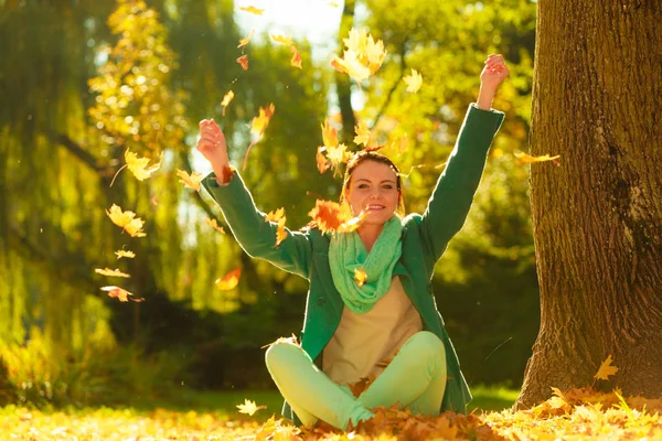 Gelukkige vrouw gooien herfst bladeren in park — Stockfoto