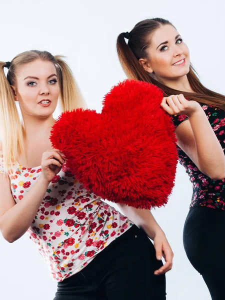 Feliz dos mujeres sosteniendo almohada en forma de corazón —  Fotos de Stock