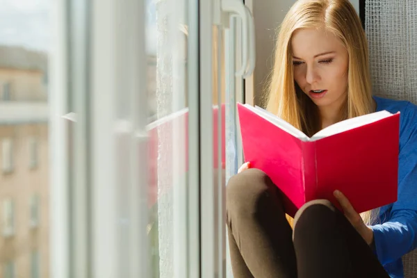 Vrouw leest op vensterbank — Stockfoto