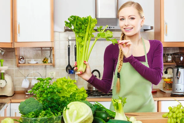 Femme dans la cuisine avec des légumes verts — Photo