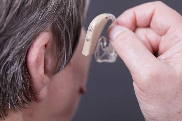 Fechar a mulher idosa usando aparelho auditivo — Fotografia de Stock