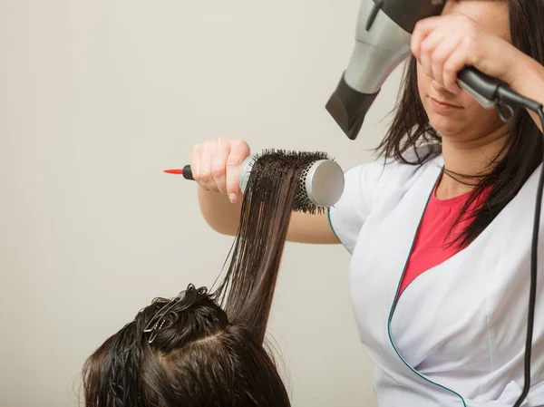 Coiffeur séchage cheveux féminins foncés en utilisant un sèche-cheveux professionnel — Photo