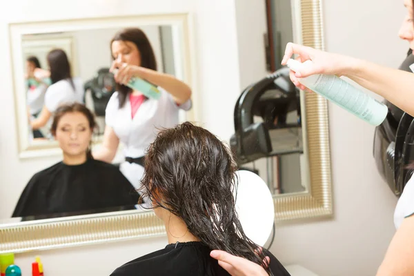 Hairdresser spraying conditioner on woman hair — Stock Photo, Image