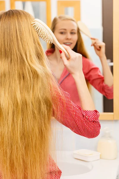 Kvinna borsta hennes långa hår i badrum — Stockfoto