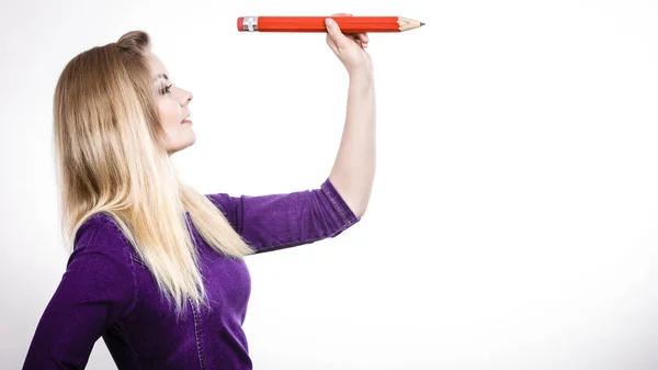 Lachende vrouw houdt grote potlood in de hand — Stockfoto