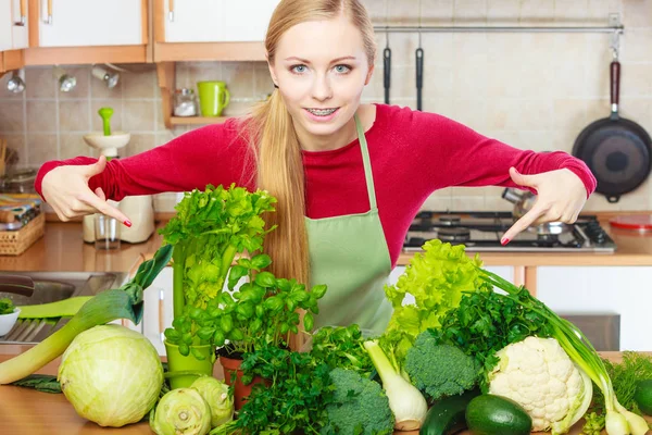 Donna in cucina con molte verdure verdi — Foto Stock