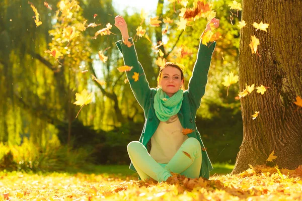 Mujer feliz lanzando hojas de otoño en el parque — Foto de Stock