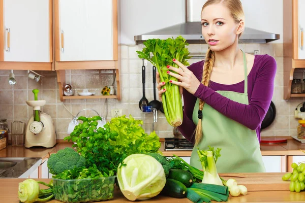Femme dans la cuisine avec des légumes verts — Photo