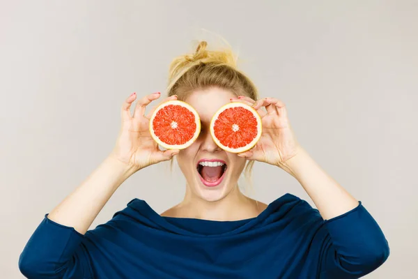 Vrouw met vruchten grapefruit helft op ogen — Stockfoto