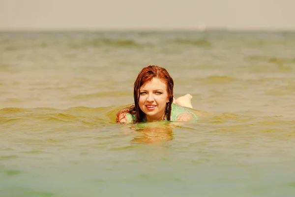 Redhead woman playing in water during summertime — Stock Photo, Image