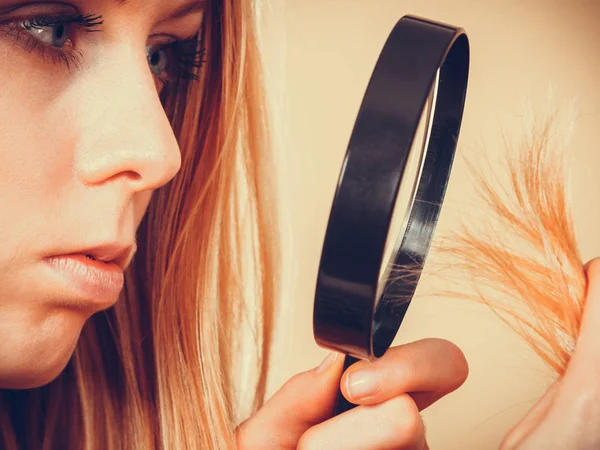 Грустная женщина смотрит на поврежденные концы волос . — стоковое фото