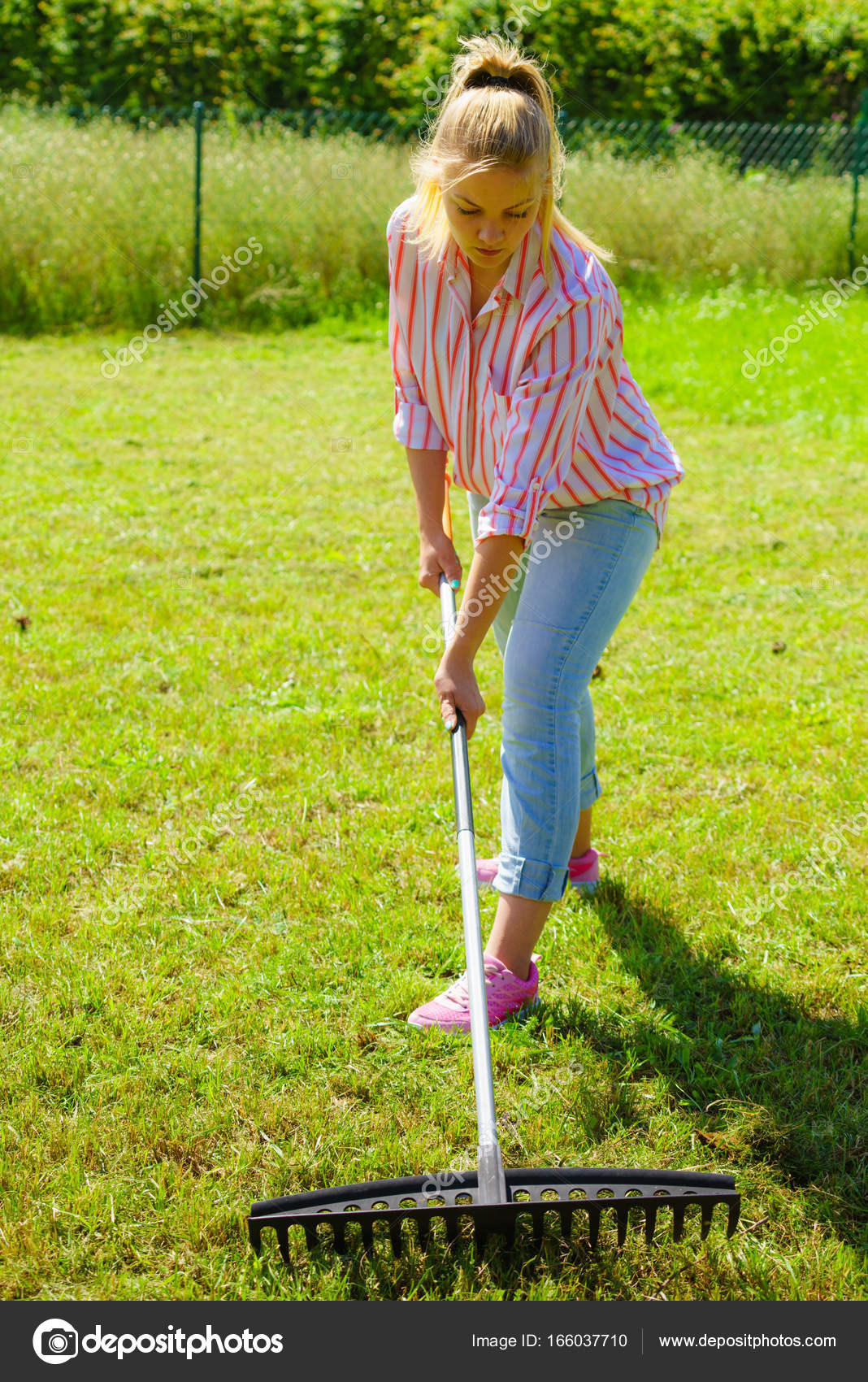 Mujer usando rastrillo para limpiar el jardín — Foto de stock