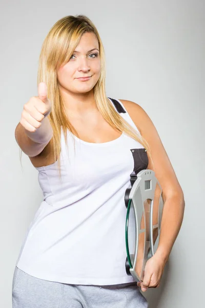Feliz mulher segurando máquina de peso mostrando polegar para cima — Fotografia de Stock