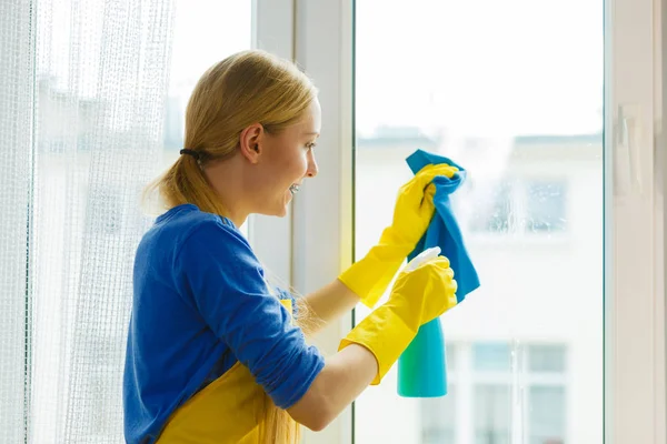 Девушка моет окно дома тряпкой для стирального порошка — стоковое фото