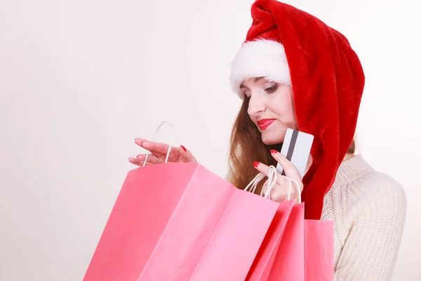 Vrouw in KERSTMUTS houdt credit card en boodschappentassen. — Stockfoto