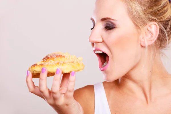 Undecided woman holds cake sweet bun in hand — Stock Photo, Image