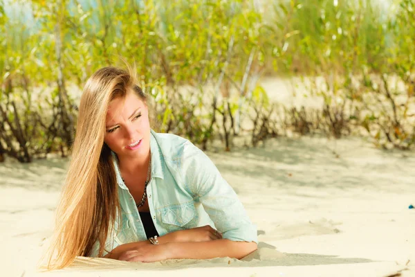 Junge Frau liegt auf grasbewachsener Düne — Stockfoto