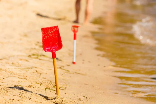 Dwa czerwone zabawka łopaty w piasku na plaży — Zdjęcie stockowe