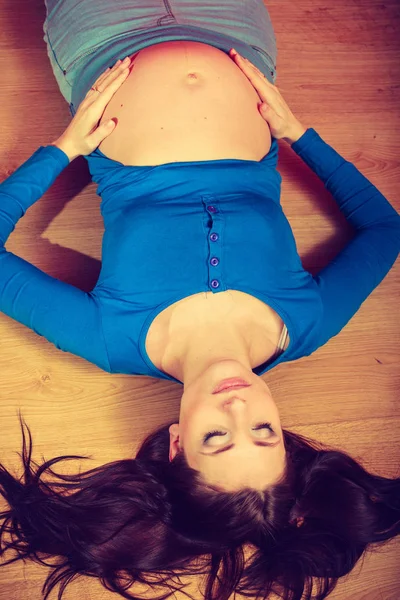 Žena ležela na podlaze ukazuje její těhotné břicho — Stock fotografie