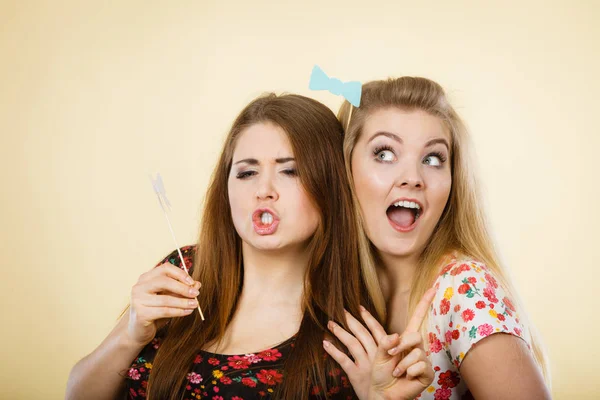 Två glada kvinnor hålla carnival accessoies på pinne — Stockfoto