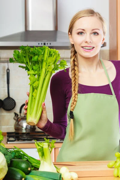 Femme dans la cuisine tient céleri vert — Photo