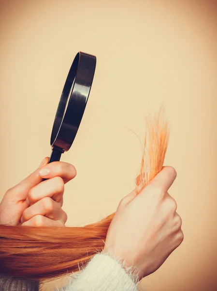 Traurige Frau blickt auf beschädigte Haarspitzen. — Stockfoto