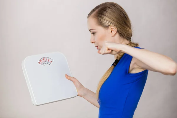 Angry woman holding bathroom scale machine — Stock Photo, Image