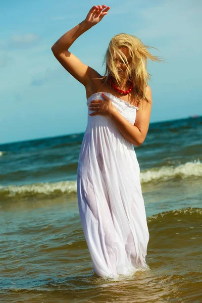 Blonde woman wearing dress walking in water — Stock Photo, Image