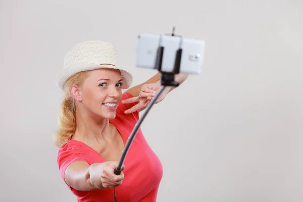 Женщина фотографирует себя с телефоном на палочке — стоковое фото
