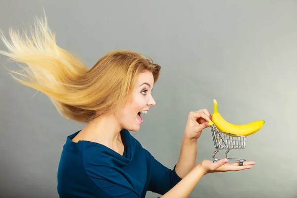 Mujer sosteniendo carrito de compras con plátano dentro — Foto de Stock