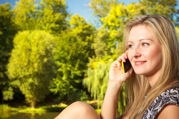Woman sitting in park, relaxing and using phone — Stock Photo, Image