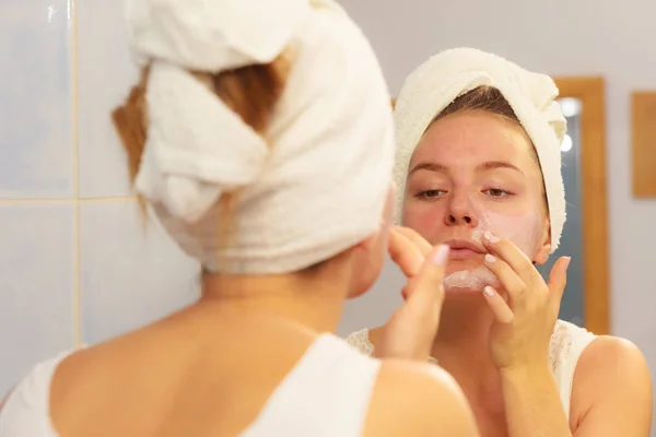 Mulher aplicando creme máscara no rosto no banheiro — Fotografia de Stock