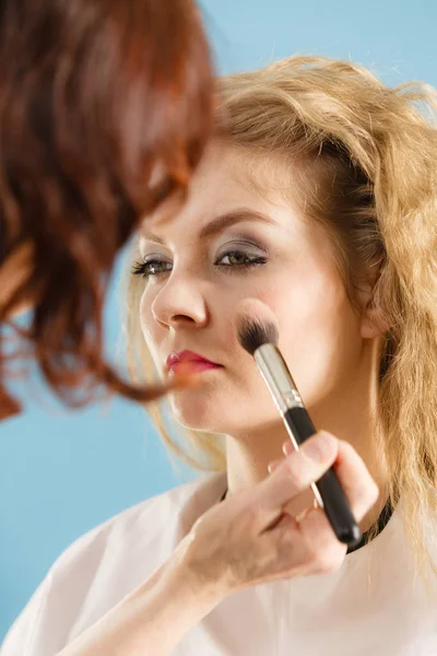 Artista de maquillaje aplicando con cepillo rouge en cheque femenino — Foto de Stock