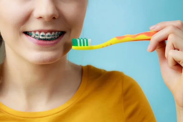 Mulher com aparelho de dentes usando escova — Fotografia de Stock