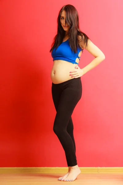 Długie włosy pasuje kobieta w ciąży na czerwono — Zdjęcie stockowe