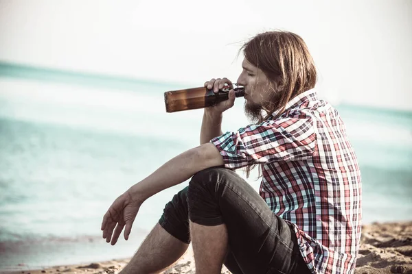 Homem deprimido com garrafa de vinho sentado na praia ao ar livre — Fotografia de Stock