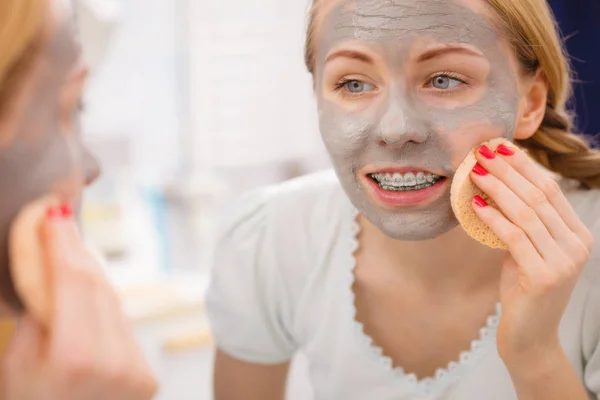 Kobieta, usuwanie błota maska do twarzy z gąbką — Zdjęcie stockowe
