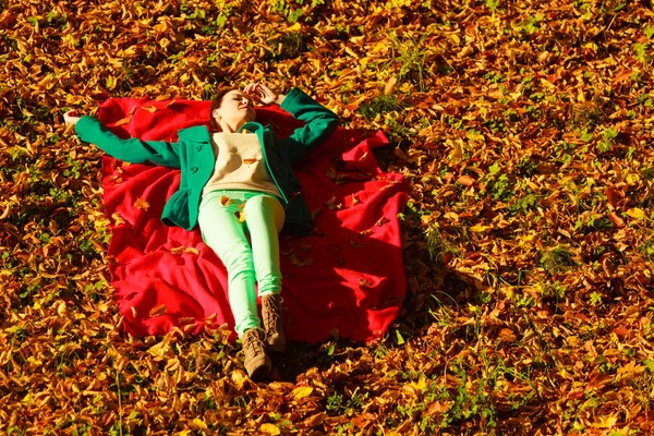 Woman sitting on autumnal leaves — Stock Photo, Image