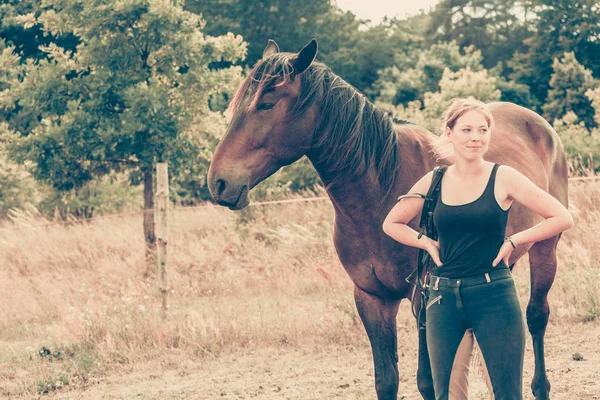 Jockey woman walking with horse on meadow — Stock Photo, Image