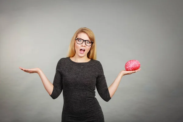 Женщина в очках в замешательстве держит мозг — стоковое фото