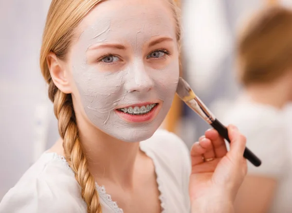 Mujer aplicando con la máscara de barro cepillo de barro en su cara —  Fotos de Stock