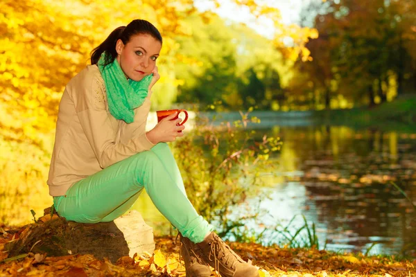 Женщина отдыхает в парке, пьет напиток из кружки — стоковое фото
