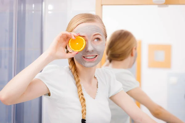 Jovem feliz tendo máscara facial segurando kiwi — Fotografia de Stock