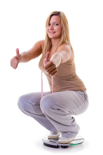 Happy woman wearing tracksuit squating on weighing machine — Stock Photo, Image