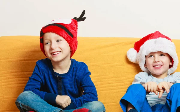 两个男孩在沙发上，头戴圣诞帽 — 图库照片