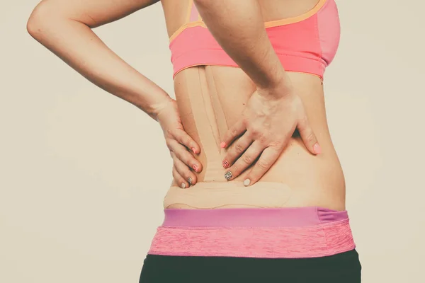 Женщина с медицинским кинезио на спине — стоковое фото