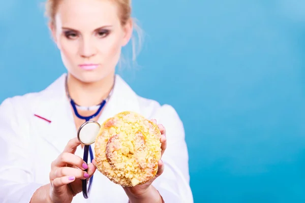 Diëtist onderzoeken zoete roll broodje met stethoscoop — Stockfoto