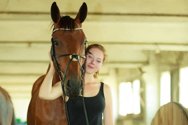 Jockey jong meisje aaien en knuffelen bruin paard — Stockfoto